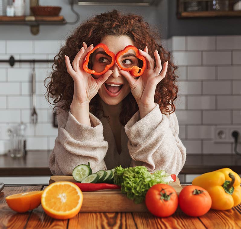 Woman holding Bell Pepper Circles in Front of Eyes Woman holding bell pepper circles in front of eyes